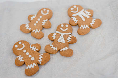 Smiling gingerbread man with sugar, spices, and vintage rolling pin on rustic, textile linen background. Top view still life with natural light.の写真素材