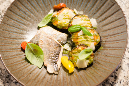 fried sea bass fillet with lemon and fresh vegetable salad close-up on a plate on the table. Vertical top view from aboveの写真素材