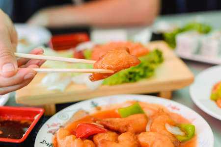 Kid using chopsticks to pick up shrimps isolated on a white background. Seafood and fruit in plate. Healthy eating lifestyle concept.の写真素材