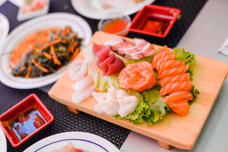Japan of raw fresh fish fillet, sashimi thin sliced mix salmon and tuna set on wooden boardの写真素材