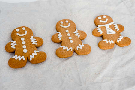 Smiling gingerbread man with sugar, spices, and vintage rolling pin on rustic, textile linen background.の写真素材