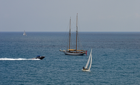 A calm afternoon scene with three sailing boats and a motor boat. France coast, Azure shore