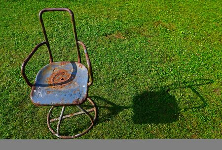 Old rusty metal chair on the lawnの写真素材