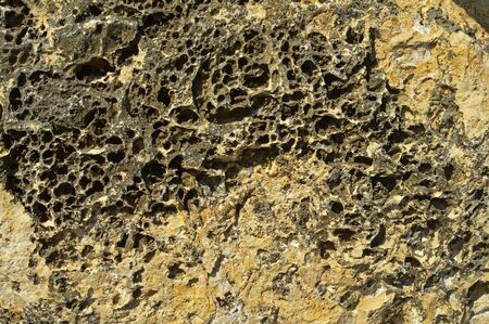 Fragment of a stone wall on the sea coast destroyed by water, wind, sun and wind