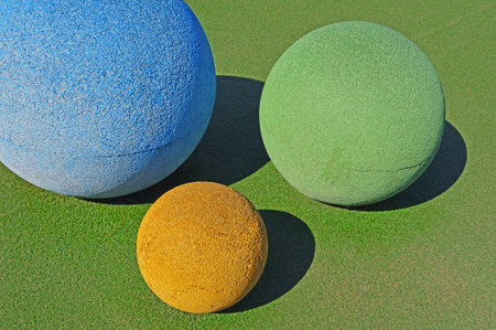 Three rubberized balls of different sizes and colors on a playgroundの写真素材