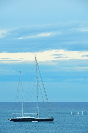 Four small sailboats next to a large yacht