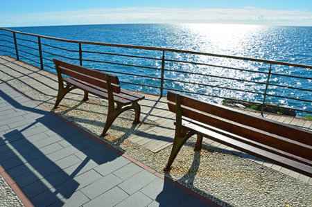 Two benches on the waterfront of the Ligurian Sea near the town of Monterosso al Mare in Italyの写真素材