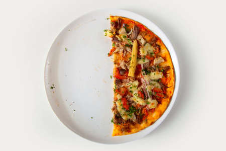 half of pizza on white plateの写真素材