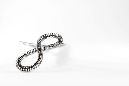Two stainless hand whisks intertwined on white background with copy space