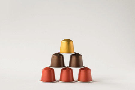 Pyramid of metallic look pods for coffee machine on plain white background