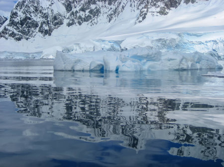 An iceberg reflected in the calm blue waters of Antarcticaの写真素材