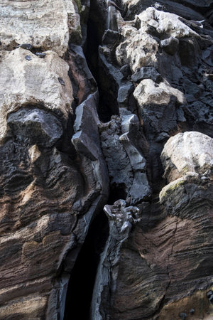 Volcanic activity has caused a vertical split in these rocks in a cliff on Galapagos Islandsの写真素材