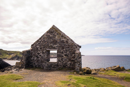 The wall of a ruined stone building provides a frame for the rugged coastline of the Moray Firthの写真素材