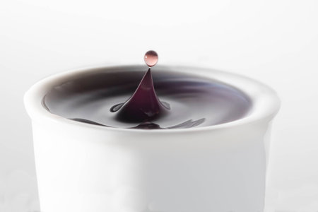 Colored water drop in white cup against white backgroundの写真素材