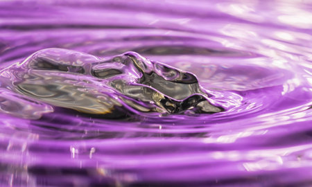 Abstract metalic look image of the wave created by a water drop on water with purple reflectionsの写真素材