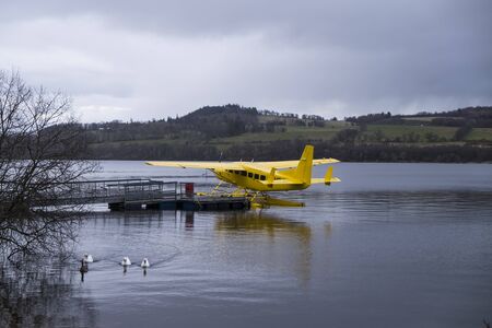 Loch Lomond, Scotland - 1 APRIL 2015 - Bright yellow Loch Lomond Seaplane moored on Loch Lomond beside Cameron House Hotel under dull grey April skies.のeditorial素材
