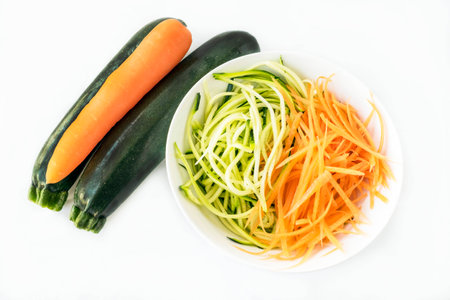 Two zucchini courgettes and carrot with some spiralized in white bowl on white backgroundの写真素材