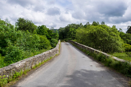 Ancient single track stone hump back bridge over the River Balvag at Balquhidder, Scotland.の写真素材