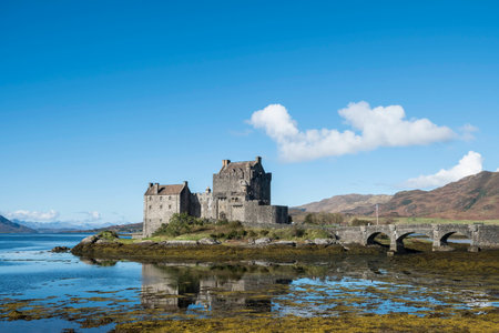 Iconic Scottish scene of Eilean Donan Castle, beautiful 13th century fortification at Dornie, Kyle of Lochalsh in the Scottish Highlands with clear blue sky and reflectionsのeditorial素材