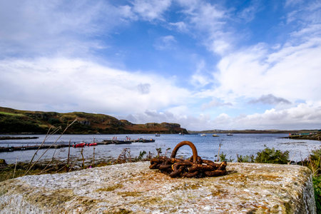 Beautiful bay in Isle of Skye Scotland with small boats, rugged coastline and concrete block with...