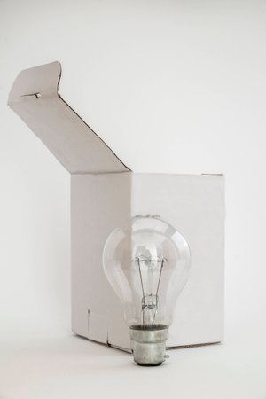 Plain white box with lid open and light bulb in front. Isolated on white background leaving copy...