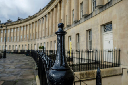 Selective focus on black wrought iron railings with the sweep of grand Georgian architecture of Royal Crescent Bath England in backgroundのeditorial素材