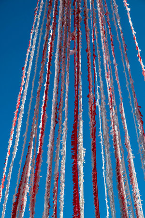 Bright colorful red and white garland bunting fluttering in the breeze against clear blue skyの写真素材