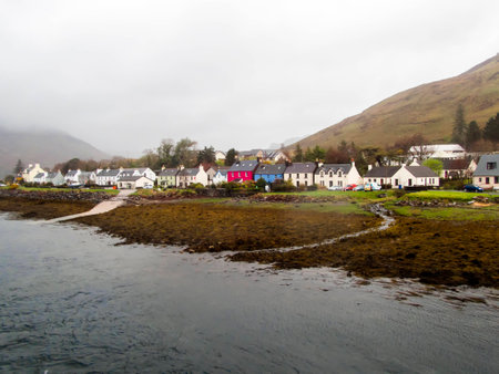Scottish scene in the rain and mist. The beautiful small former fishing village of Dornie on the shore of Loch Alsh and Loch Duich with its colorful houses and cottages and mountain backdopの写真素材