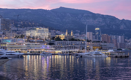 Looking across the exclusive harbour at Monte Carlo Monaco with its famous casino lighting up at duskの写真素材