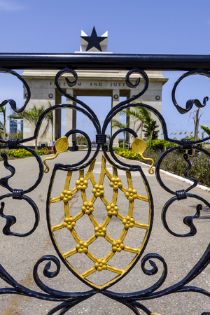 Looking through ornate railings to Black Star Monument in Independence Square Accra Ghana against blue skyの写真素材