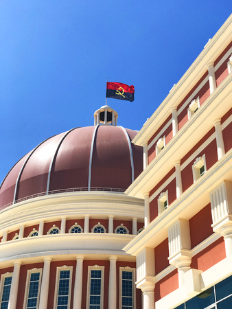 LUANDA, ANGOLA - MARCH 29 2018: Stunning architecture of Angolan Parliament building and flag in capital city of Luanda against blue skyのeditorial素材