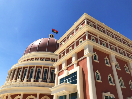 LUANDA, ANGOLA - MARCH 29 2018: National flag flies over impressive architecture of Angolan Parliament building and flag in capital city of Luanda against blue skyのeditorial素材