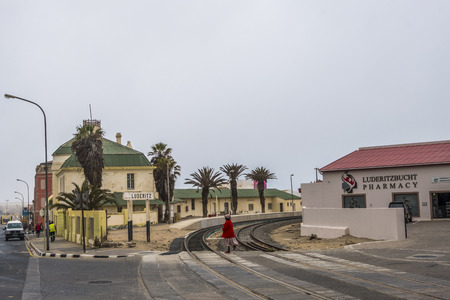 LUDERITZ, NAMIBIA - MARH 23 2018: Local lady dressed in red crosses the rail tracks at Luderitz Railway Station, part of TransNiamib Railway and built in 1904のeditorial素材