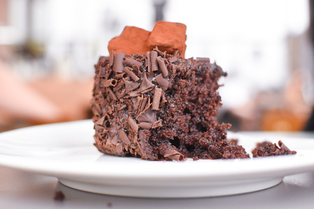 closeup of half eaten chocolate cake. view close up half of tasty chocolate cake on white plate.