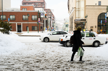 Winter street scene walking on the snow - people walking on snow covered the street during winter and heavy snow in Otaru Hokkaido, Japan. 27-1-2016のeditorial素材