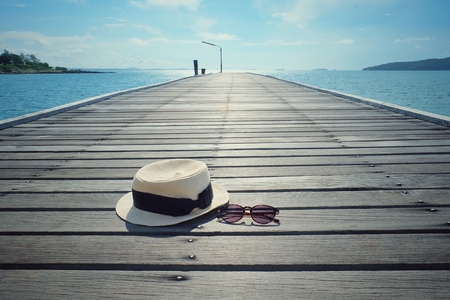 Hats and glasses on wooden bridge with clear blue sky for relaxing.の写真素材