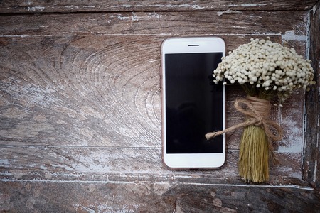 Bouquet flowers, gift box and phone on vintage and old wooden table.の写真素材