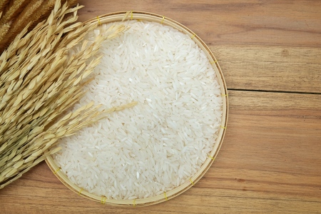 Paddy and white rice on wooden background