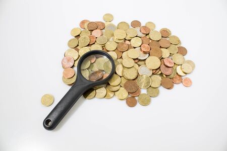 Coins and magnifying glass in a white background compositionの写真素材