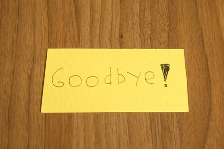 Goodbye handwrite on a yellow paper with a pen on a table compositionの写真素材