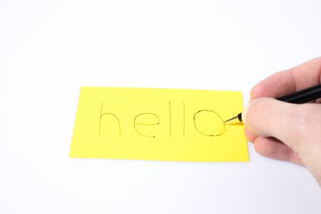 Hello handwrite with a pen and a hand on a yellow paper composition