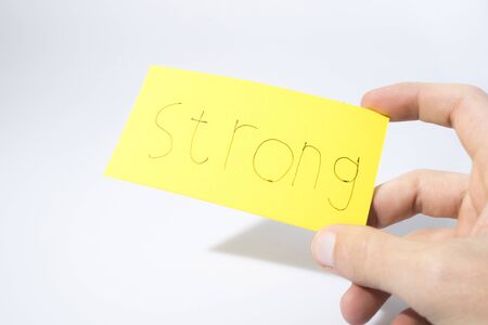 Strong handwrite with a hand on a yellow paper composition