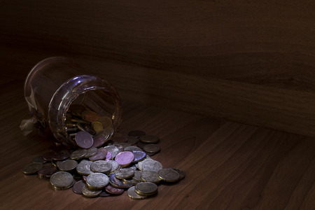 Jar of glass full of euro coins on a table using light painting technique compsoition
