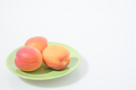 Fruit composition, apricots on a green plate isolated in a white background compositionの写真素材