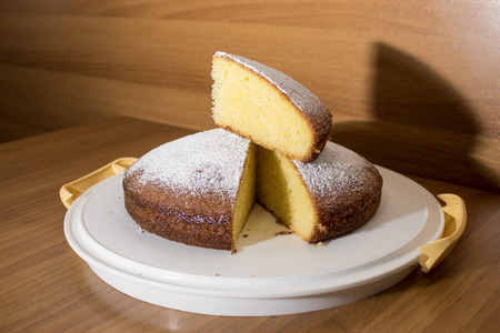 Slice of a delicious cake with powdered sugar on a wood table composition
