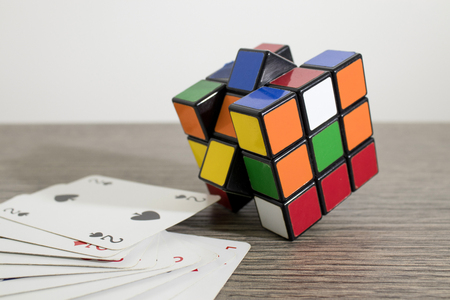 Gaming cards and a colored rubik cube on a decrated wood table compositionのeditorial素材