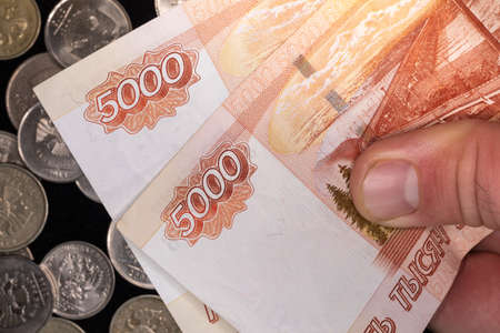 5000 Russian ruble bills on the background of coins