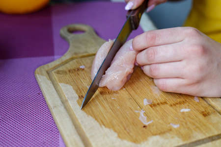 woman cuts of chicken on a cutting boardの写真素材