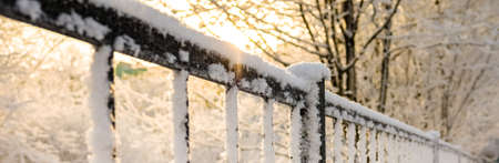snow-covered fence in snow in sunlightの写真素材