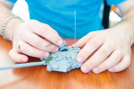a man assembles a plastic tank model toy, assembles a tank turretの写真素材